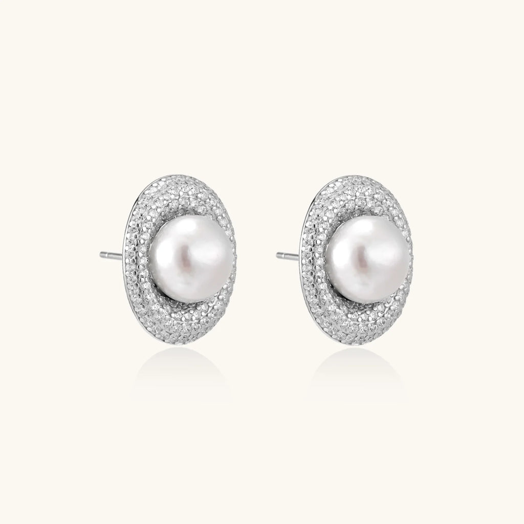 Oval rhodium-plated silver studs featuring freshwater pearls surrounded by pavé crystal halo on white background