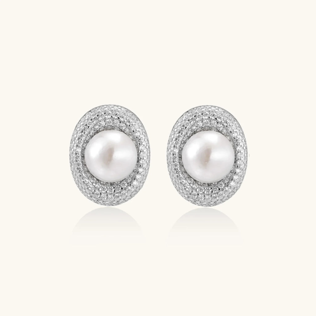 Oval rhodium-plated silver studs featuring freshwater pearls surrounded by pavé crystal halo on white background