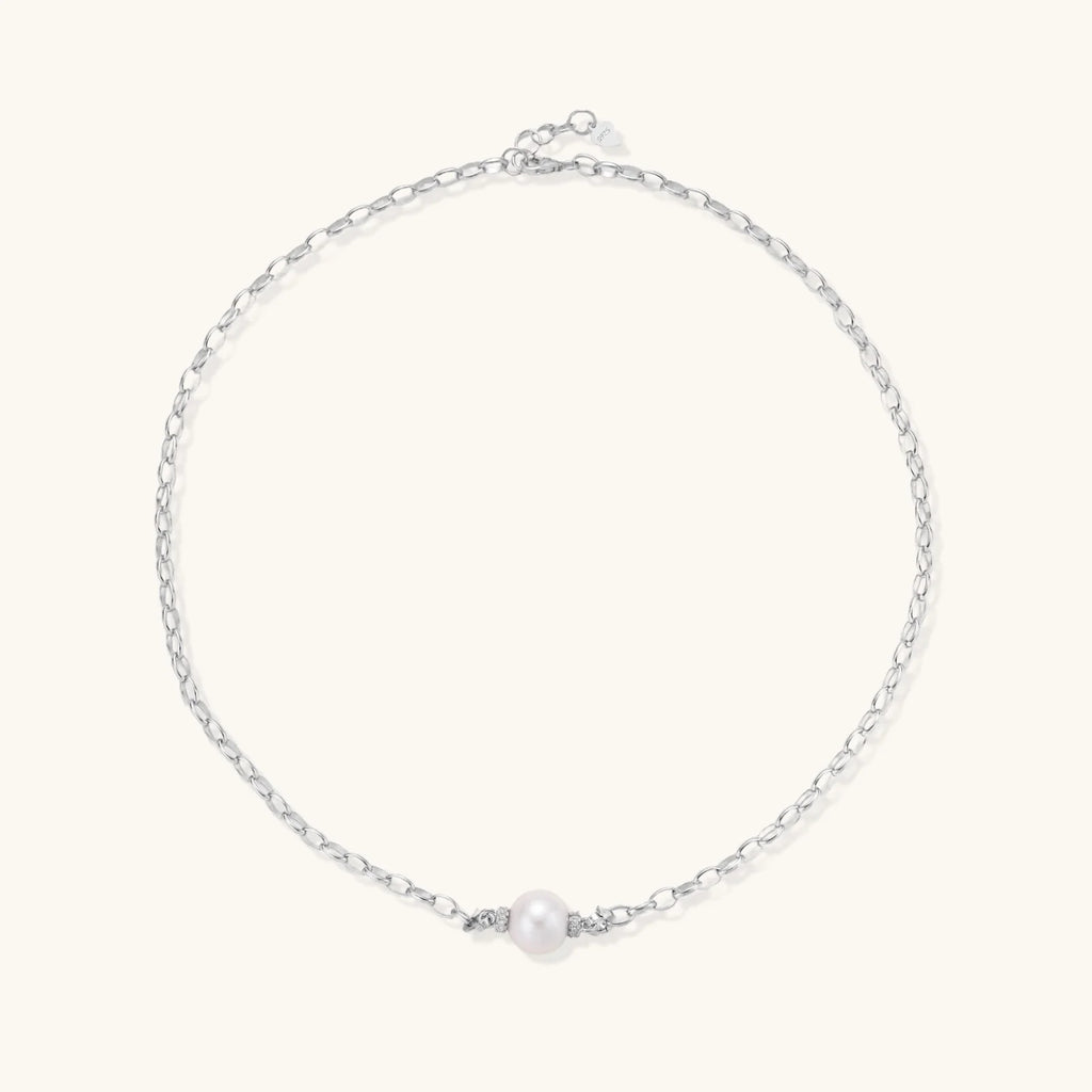 Dainty rhodium-plated silver chain necklace with centered 10mm freshwater pearl and crystal accents on cream background