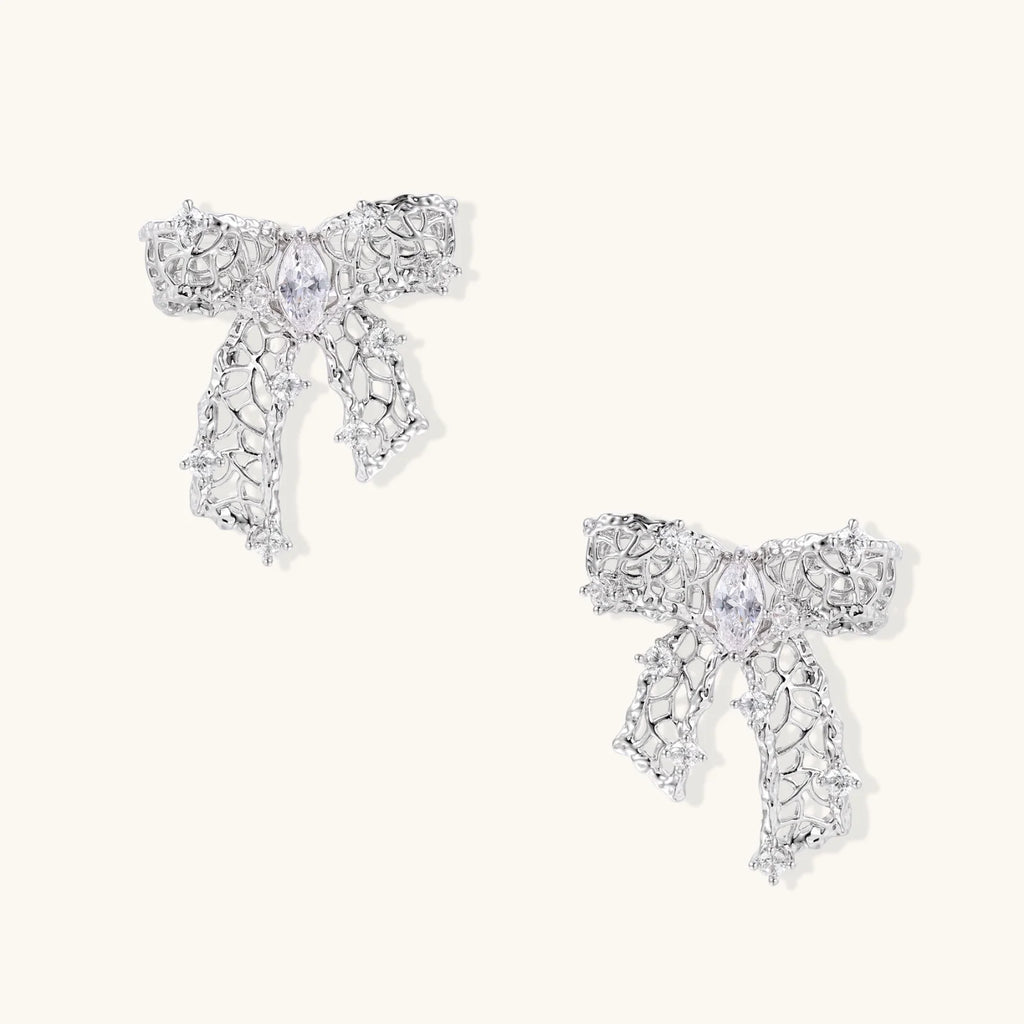 Filigree bow-shaped earrings with marquise center stone and lattice ribbon tails in gold and silver finishes