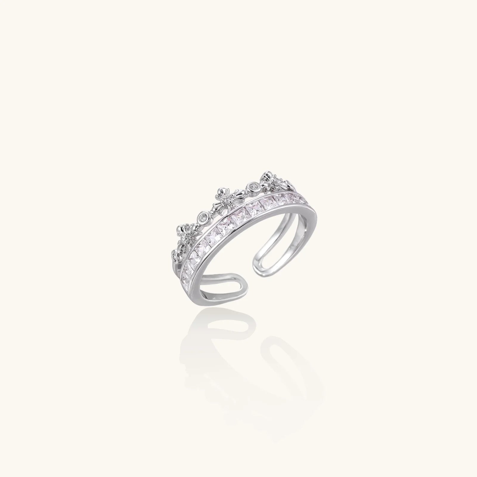 Silver-toned adjustable crown ring with channel-set square zirconia stones and delicate floral details on white background