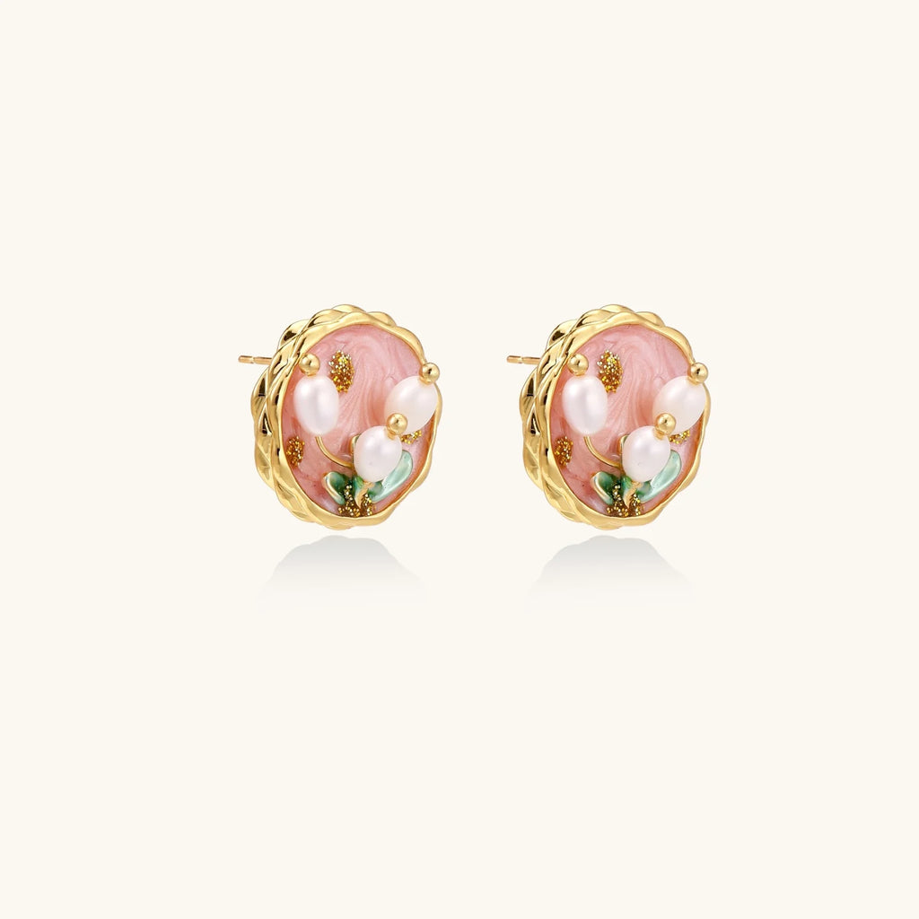Round stud earrings with pink enamel, three white freshwater pearls, green leaves, and gold-plated braided border