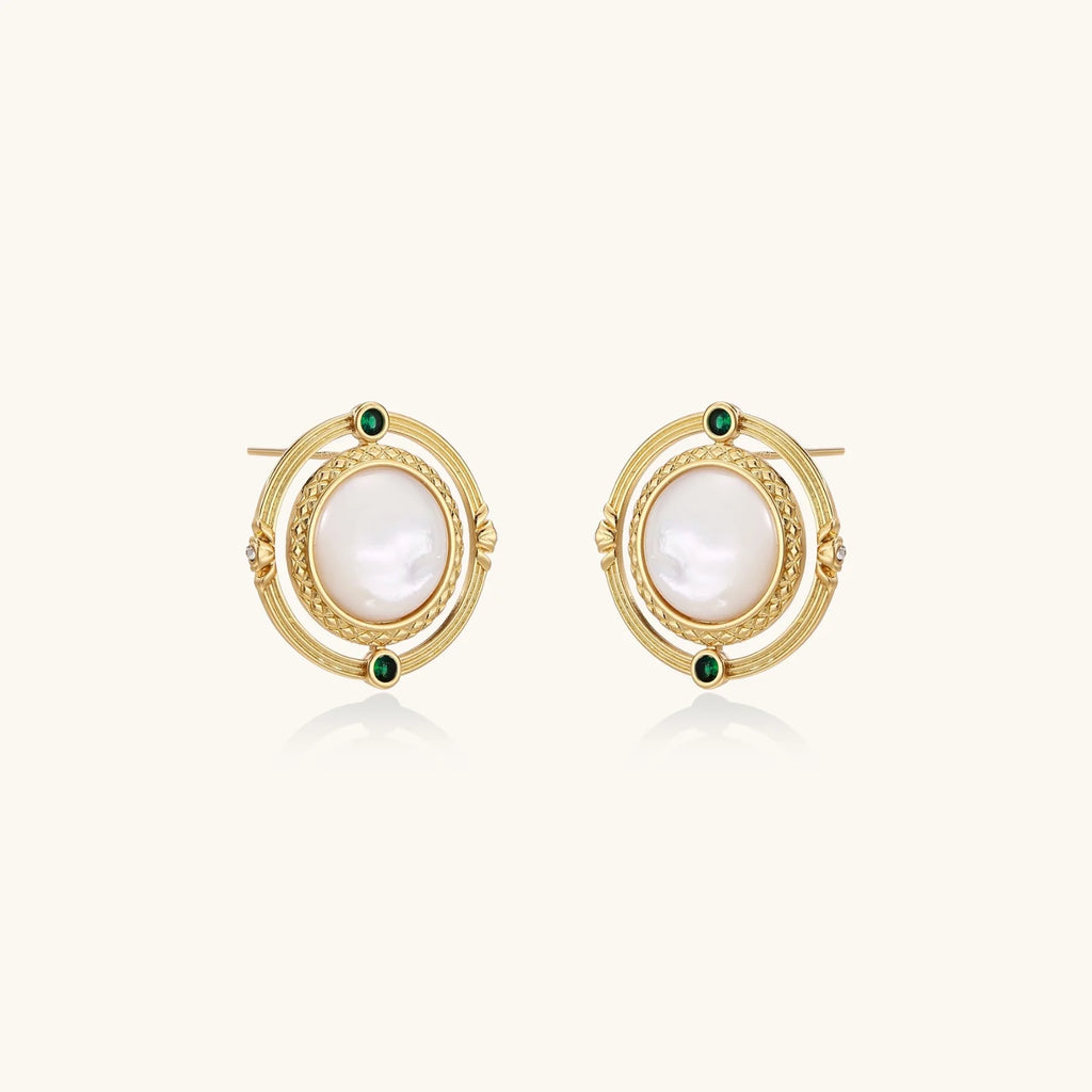 Circular gold stud earrings with iridescent mother-of-pearl center and green zirconia accents on cream background.