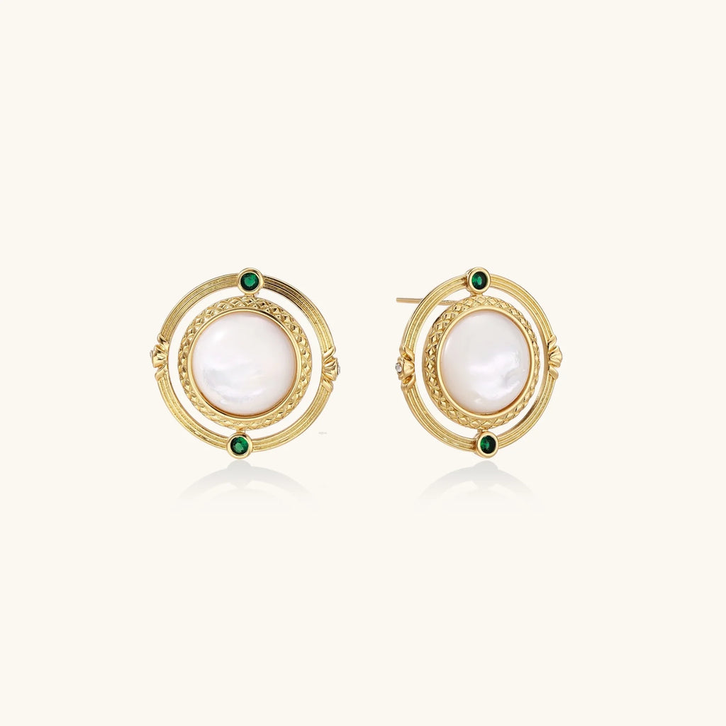 Circular gold stud earrings with iridescent mother-of-pearl center and green zirconia accents on cream background.