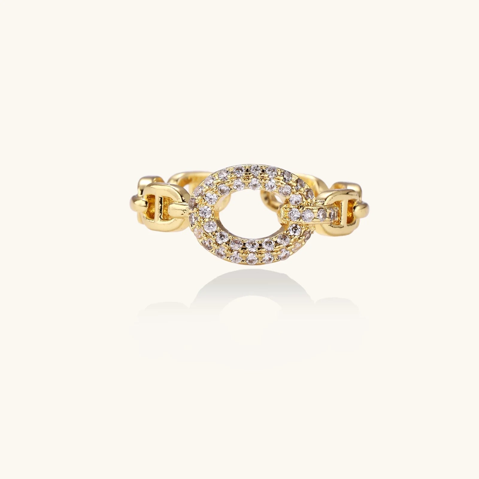 Gold-plated brass chain link ring with one oval CZ-pavé segment on cream background, adjustable cuff style.
