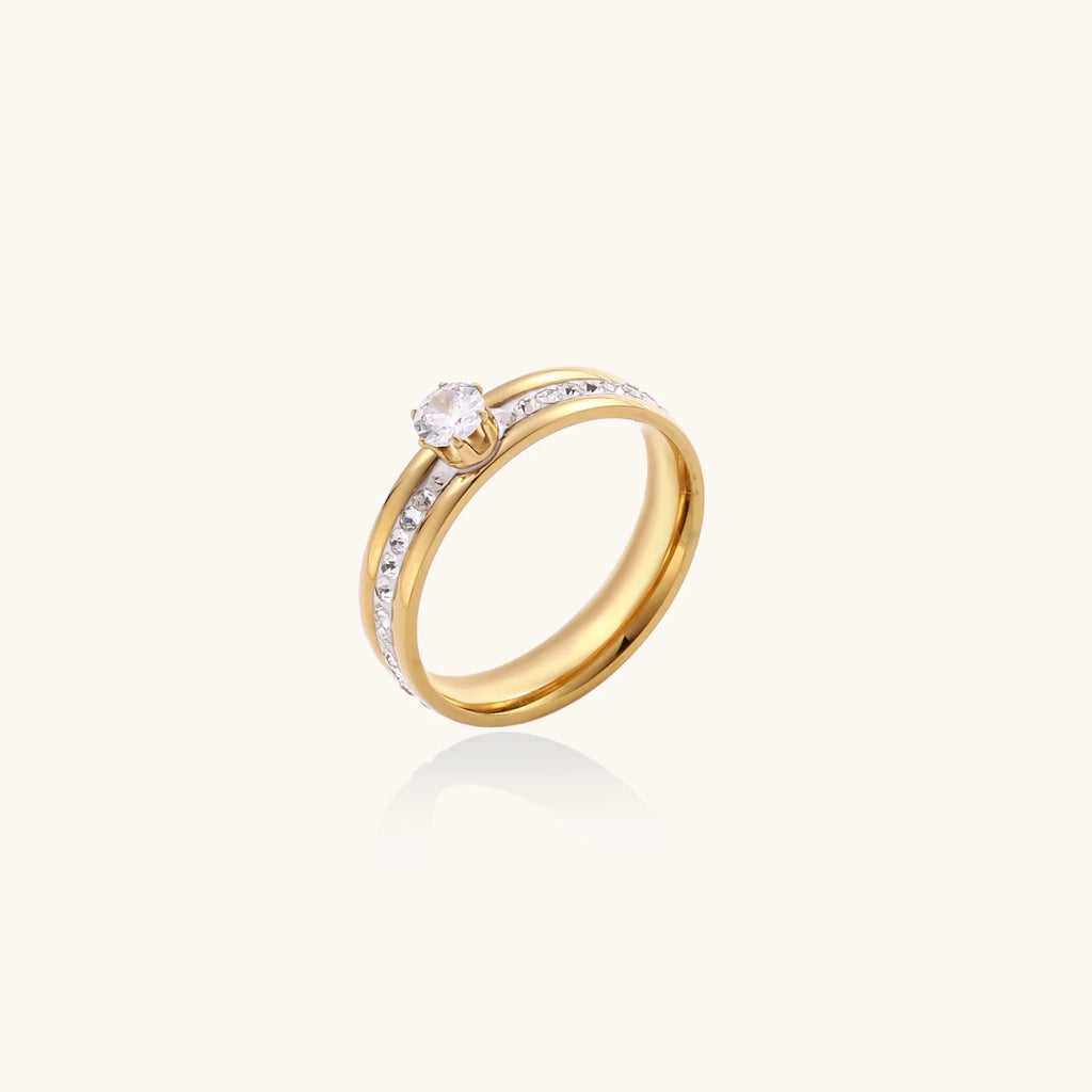 Gold-plated double-band ring with center rhinestone solitaire and channel-set stones on white background