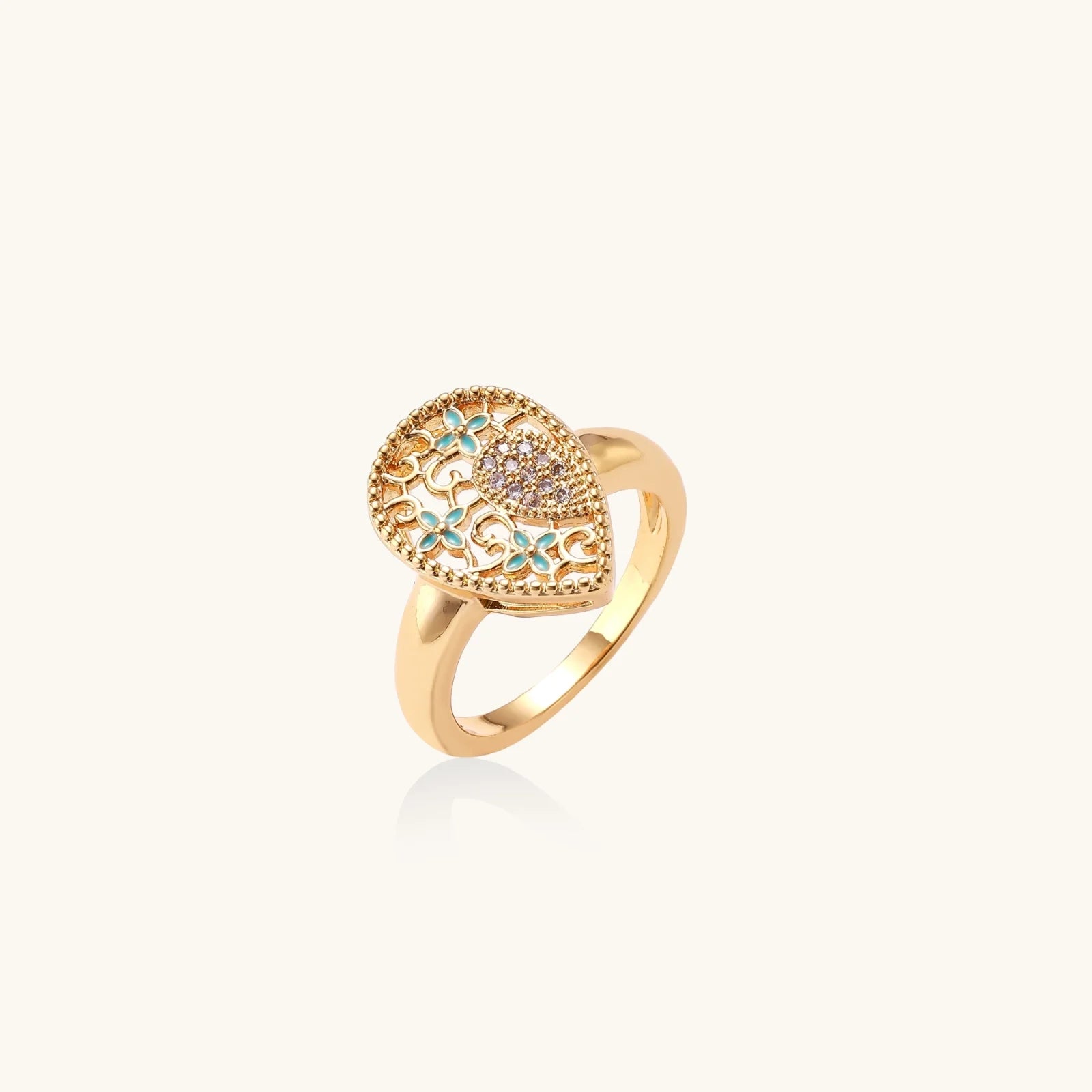 Teardrop-shaped gold-plated ring with turquoise enamel flowers and crystal pavé detail on cream background