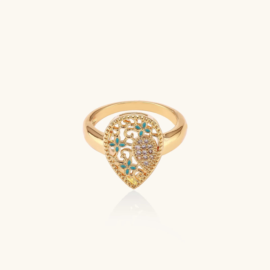 Teardrop-shaped gold-plated ring with turquoise enamel flowers and crystal pavé detail on cream background