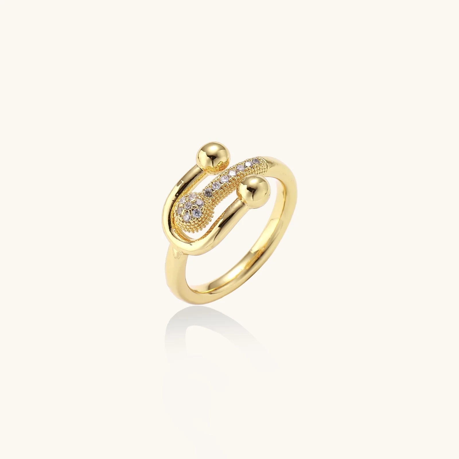 Gold-plated brass ring with safety pin design featuring pavé cubic zirconia stones and dual sphere ends