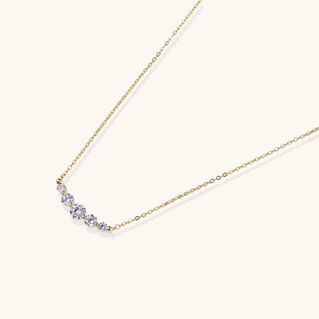 Delicate 14K gold-plated necklace with five graduated zirconia stones arranged in a curved arc on fine chain