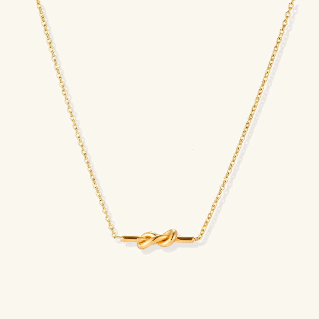 Dainty 18K gold plated necklace with infinity knot pendant on delicate chain against white background