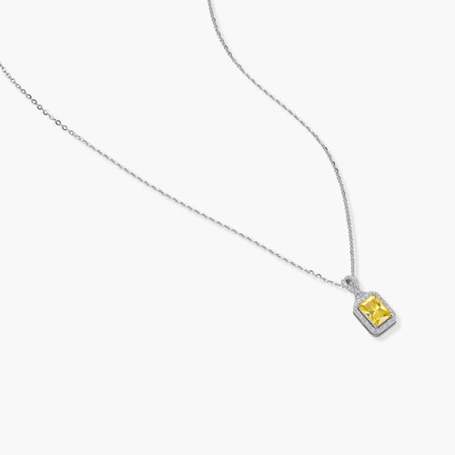 Rectangular yellow moissanite pendant in sterling silver halo setting on delicate chain against cream background.