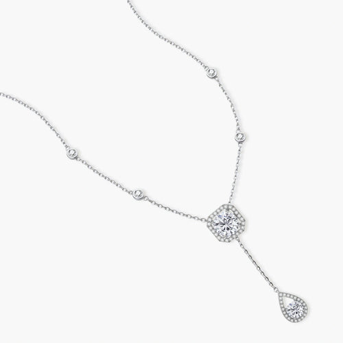 Sterling silver necklace with cushion-cut moissanite in halo setting and teardrop pendant, displayed on cream background.