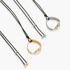 Adjustable black cord necklace with circular gold pendant featuring sparkly crystal accents on white background.
