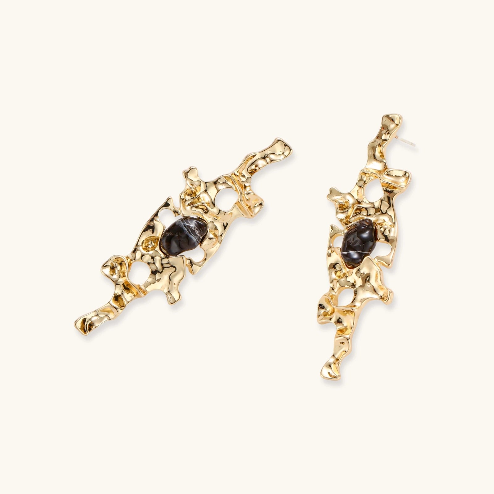 Elongated sculptural earrings with organic openwork design in eco-zinc alloy and dark resin accents on white background.