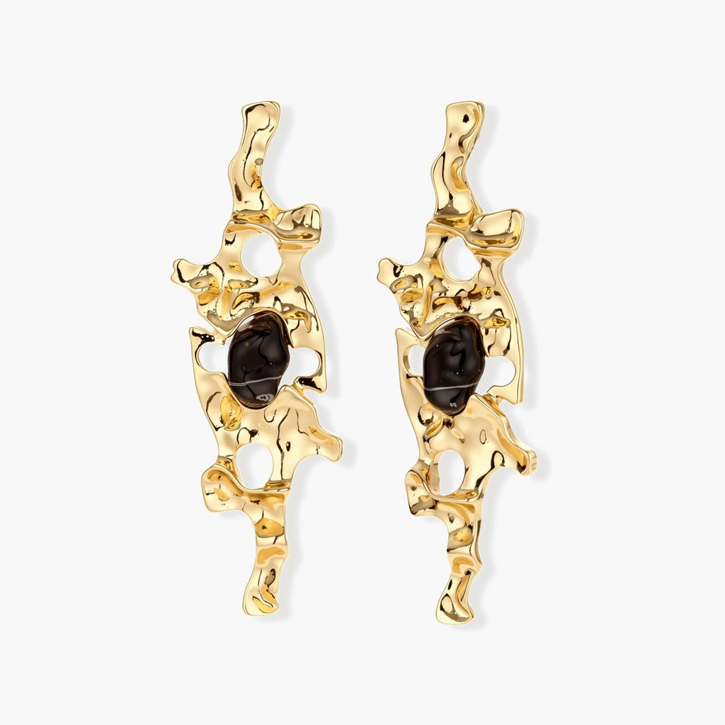 Elongated sculptural earrings with organic openwork design in eco-zinc alloy and dark resin accents on white background.