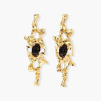 Elongated sculptural earrings with organic openwork design in eco-zinc alloy and dark resin accents on white background.