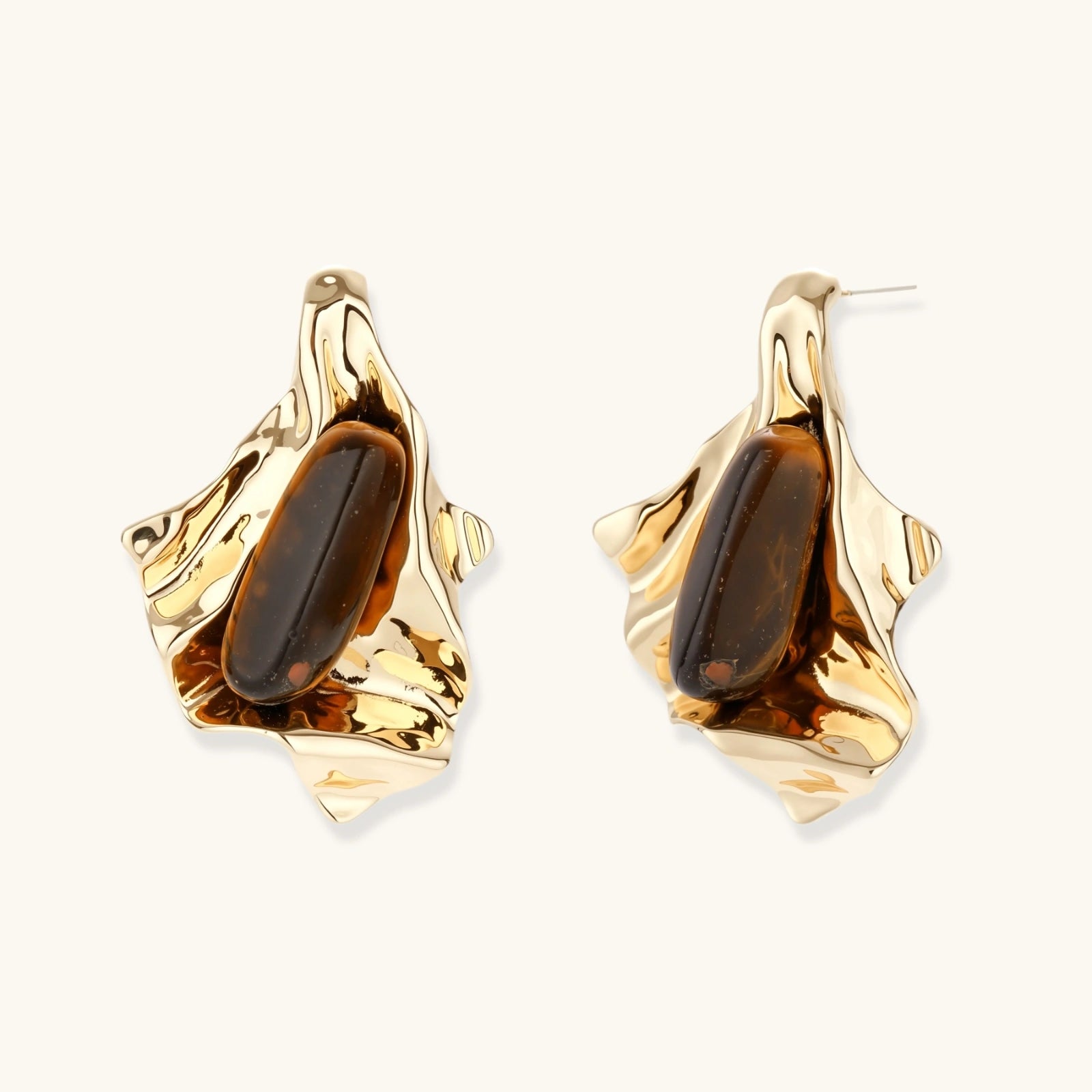 Sculptural stud earrings with organic twisted metal design holding brown gemstones, shown in gold and silver finishes.