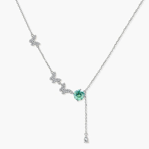 Sterling silver necklace with butterfly charms, green moissanite center stone, and teardrop crystal pendant on white background.