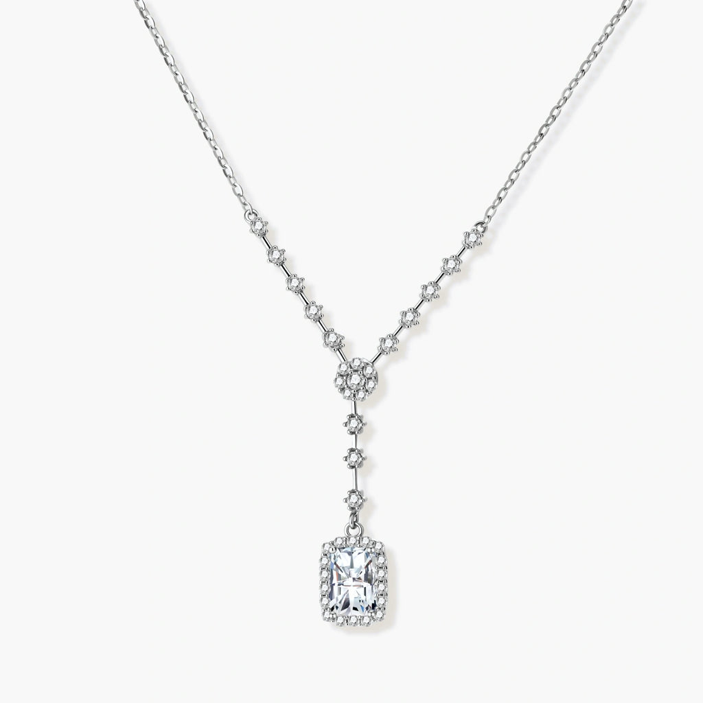 Sterling silver Y-necklace with rectangular moissanite pendant in halo setting and cascading accent stones on white background.