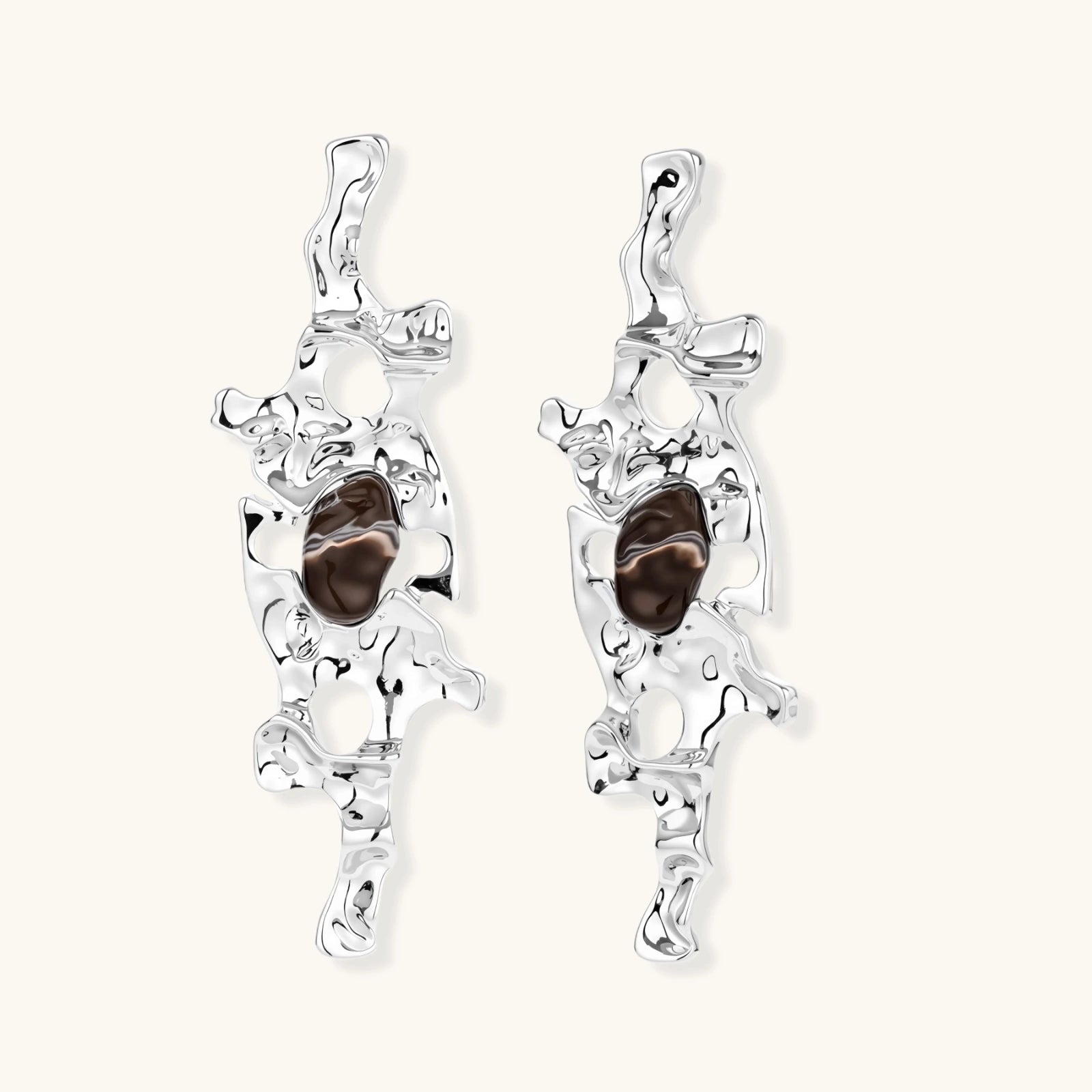 Flowing silver-toned earrings with organic liquid shapes and embedded brown resin stones on white background.