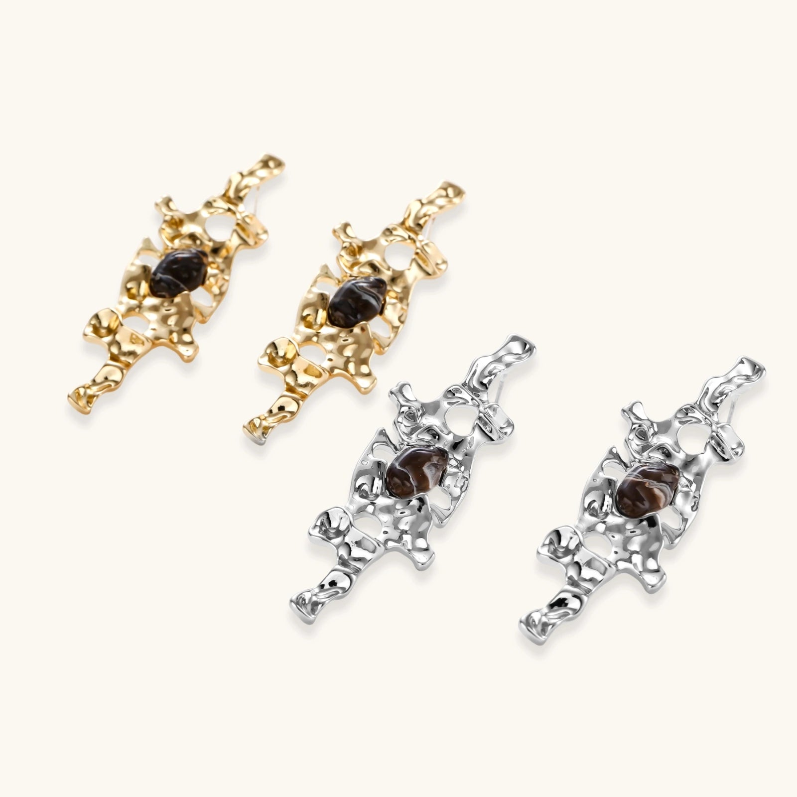 Flowing silver-toned earrings with organic liquid shapes and embedded brown resin stones on white background.