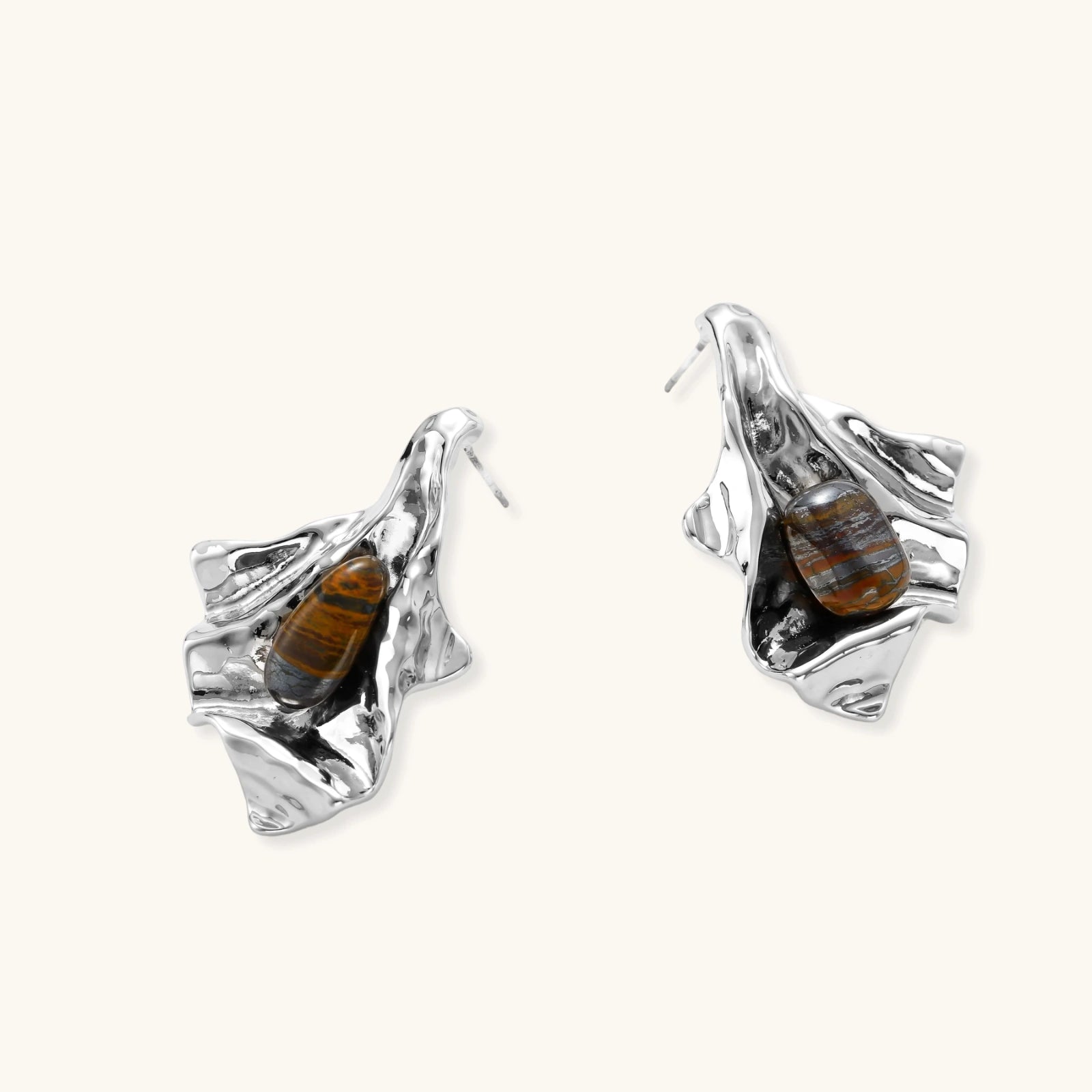 Silver sculptural earrings with flowing molten forms and amber gemstones, featuring 925 silver posts on white background.