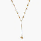 Adjustable gold lariat necklace with freshwater pearls nested in delicate cage settings and Y-shaped tassel drop